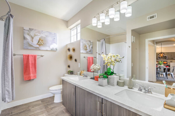 Bathroom with wood cabinets, stone counters, large mirror, and tiled shower tub.