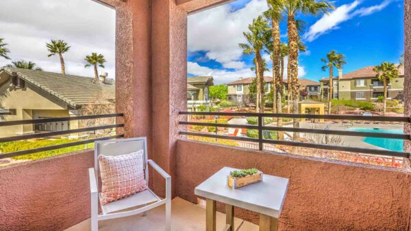 Balcony with outdoor furniture and metal railing overlooking pool area.