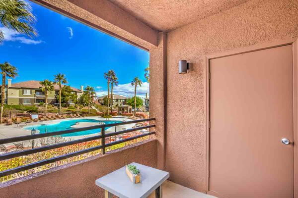 Balcony with outdoor furniture and metal railing overlooking pool area.
