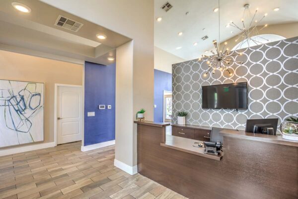 Lobby with wood style floor, desk with computer and TV, chandelier, and large artwork.