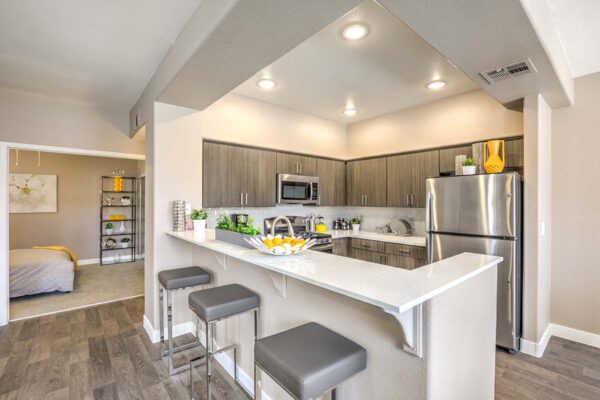 Kitchen with wood floor and cabinets, light counters, and stainless steel appliances.
