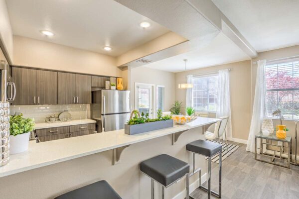 Kitchen with wood floor and cabinets, light counters, and stainless steel appliances.