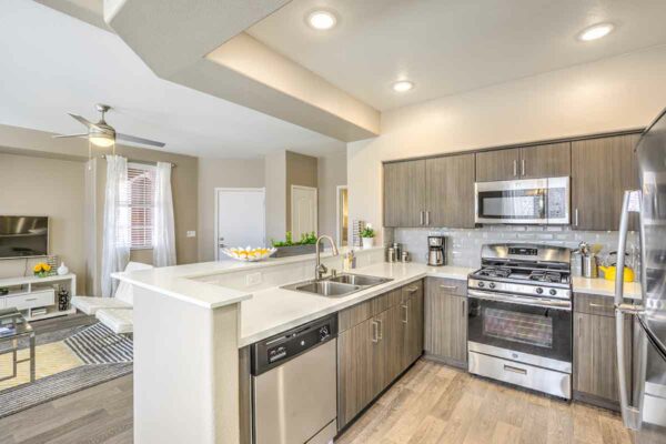 Kitchen with wood floor and cabinets, light counters, and stainless steel appliances.