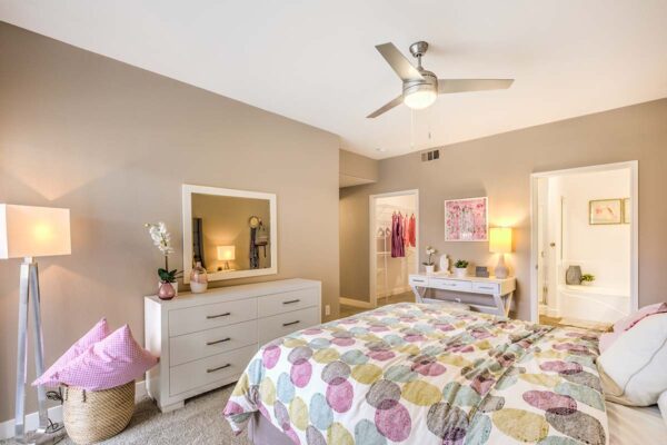 Bedroom with carpet, plush bed, dresser with mirror, and doors to closet and bathroom.