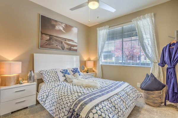 Bedroom with plush bed, bedside drawers with lamps, large artwork, and large window.