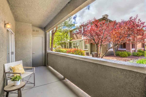 Balcony with chair and table with plant overlooking lush landscaping at Madera apartments.