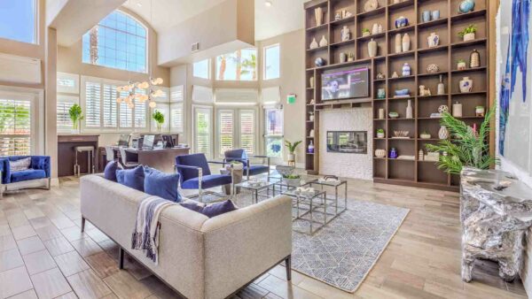 Clubroom with plush seating, computer desks with chairs, shelves with decor, and large windows.