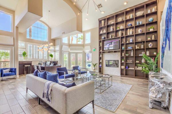 Clubroom with plush seating, computer desks with chairs, shelves with decor, and large windows.