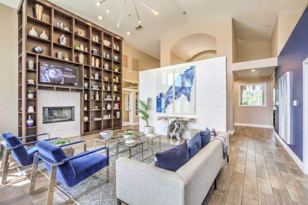 Clubroom with plush seating, computer desks with chairs, shelves with decor, and large painting.