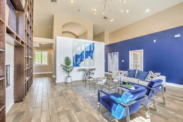 Clubroom with plush seating, computer desks with chairs, shelves with decor, and large painting.