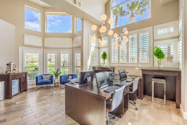 Business center with computer desks, comfortable chairs, coffee machine, and fridge.