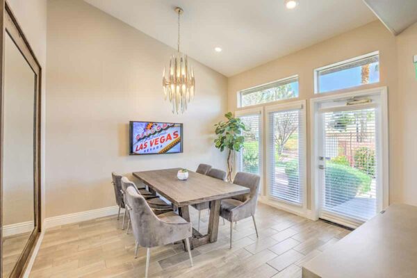 Meeting room with wood table, plush chairs, TV, chandelier, and door to outside.