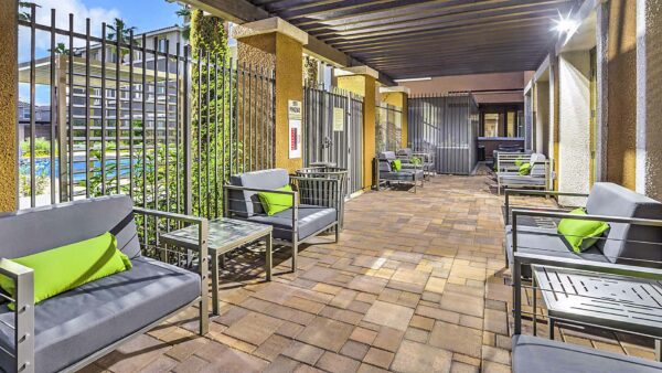 Outdoor lounge with stone paver patio, lounge chairs, and pergola roof.