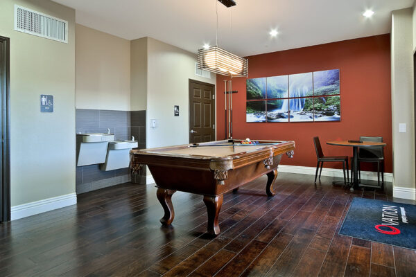Game room with wood floor, pool table, cue rack, large artwork, and drinking fountains.