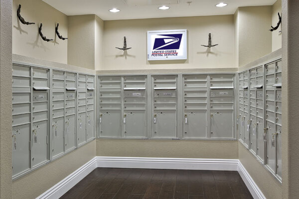 Mail room with grey mailboxes, wood tile floor, postal service sign, and small sculptures.