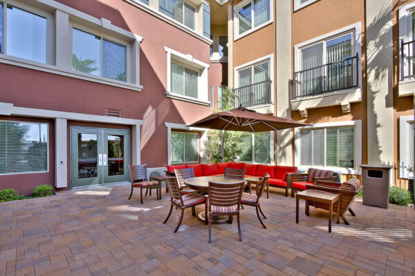 Outdoor lounge with stone paver patio, plush outdoor sectional, and dining table with chairs.