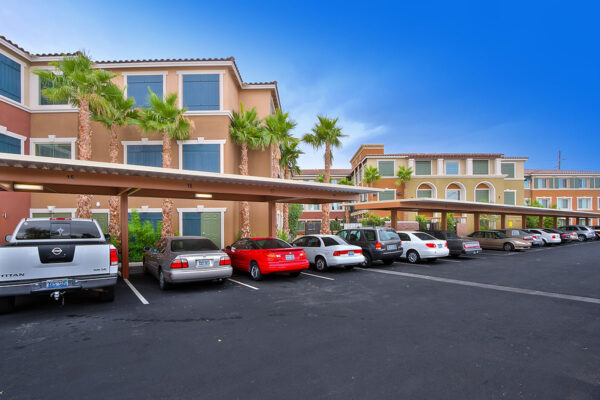 Minuet apartments with classic architecture, tall palm trees, and ample covered parking.
