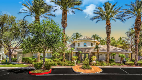 Clubhouse at Adiamo with ample visitor parking and tall palm trees.