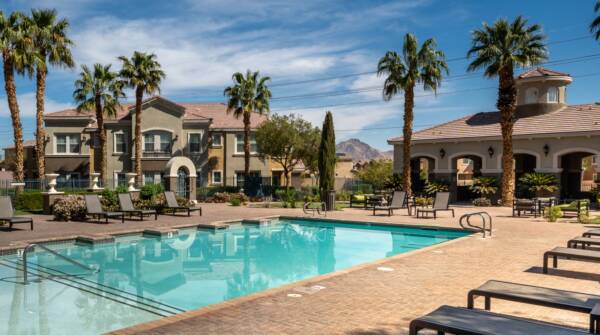 Arzano apartments pool area with lounge chairs and palm trees.