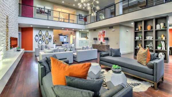 Elevate community clubroom with wood tile floor, plush seating, glass light fixture, and eclectic decor.