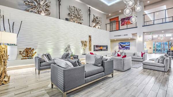 Inspire community clubroom with wood tile floor, plush couches, glass light fixture, art sculpture, and mezzanine.