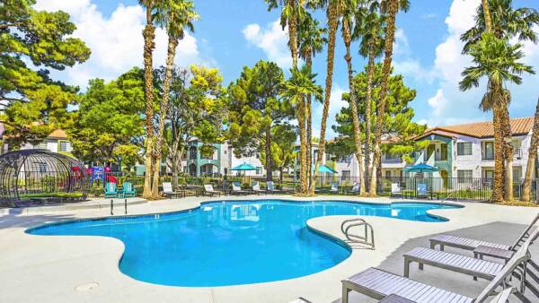 The Grove pool area with lounge chairs, gazebos, lush landscaping, and tall palms.