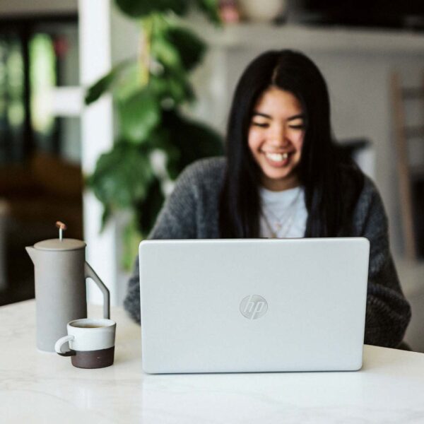 Person smiling and working on their laptop computer.