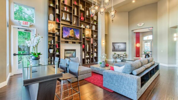 Clubhouse with vaulted ceilings, plush seating, fireplace, and shelves with decor.