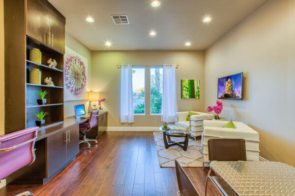 Business center with computer desks, shelves with decor, and plush seating.