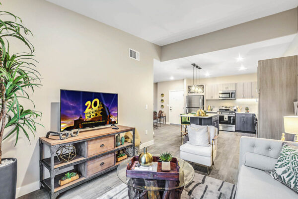 Living room with plush seating, industrial shelves with TV, and glass coffee table with decor.