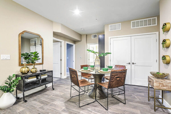 Dining area with glass dining table, shelves with decor, and large framed mirror.