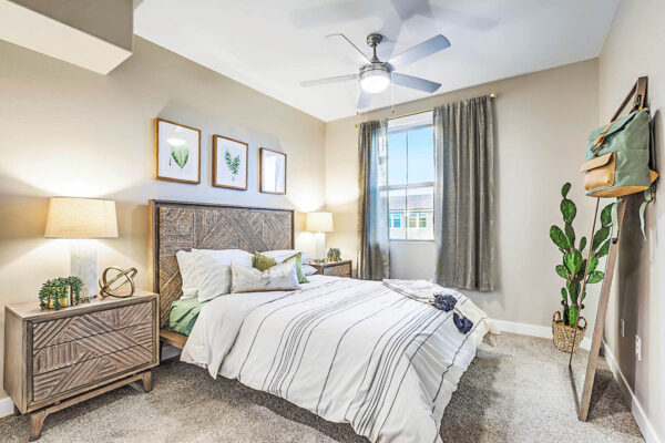 Bedroom with carpet, plush bed with headboard, bedside drawers with lamps, and large window.