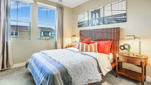 Bedroom with plush bed, wood headboard, bedside drawers with lamps, and large window.