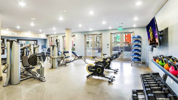 Fitness center with cardio machines, weight equipment, TV, and doors to courtyard.