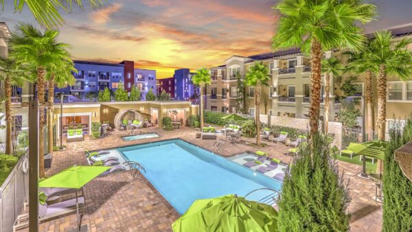 Overhead view of pool area with lounge chairs, umbrellas, gazebo, and tall palm trees.