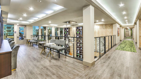 Clubhouse mezzanine with plush benches, round tables, and railings overlooking lounge.