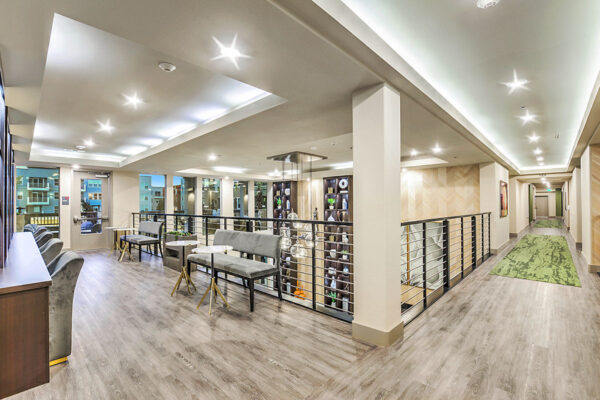 Clubhouse mezzanine with plush benches, round tables, and railings overlooking lounge.