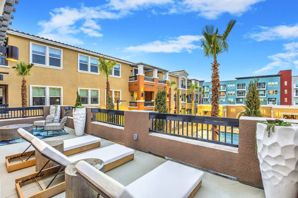 Rooftop lounge with lounge chairs, dining tables, and potted plants overlooking pool area.