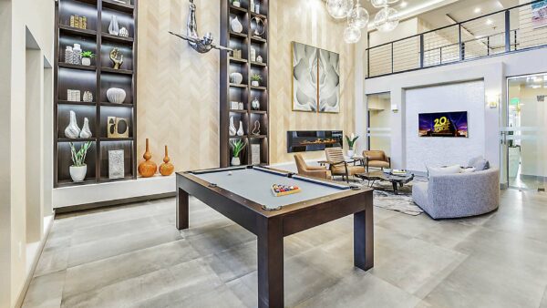 Clubhouse with pool table, plush seating, shelves with decor, and large framed artwork.