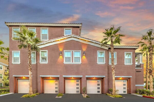 Radiance at Grand Canyon apartments with tuck under garages, lush landscaping, and tall palm trees.