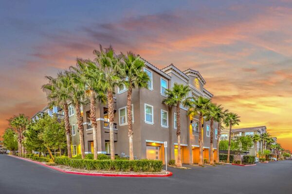 Radiance at Grand Canyon apartments with tuck under garages, lush landscaping, and tall palm trees.