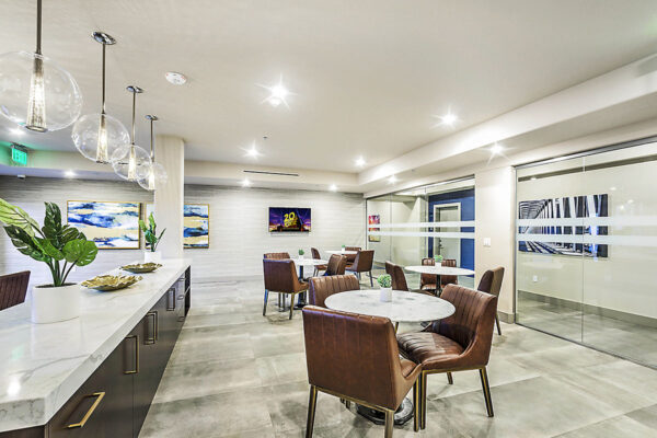 Clubhouse with dining tables, stone counter with wood cabinets, glass walls, and TV.