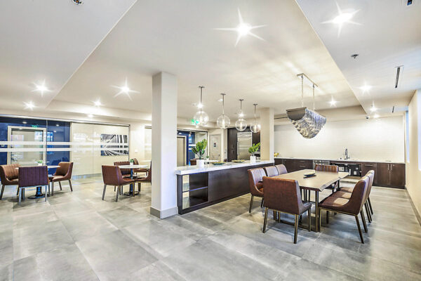 Clubhouse with dining tables, stone counter with wood cabinets, glass walls, and demo kitchen.