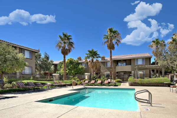 San Croix pool area with lounge chairs, BBQ grills, lush landscaping, and tall palms.