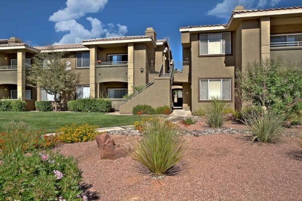 San Croix apartments with rocky landscaping, tall trees, paved walkways, and green lawns.