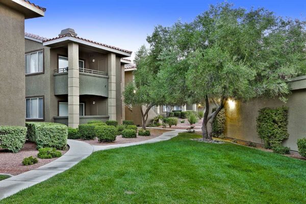 San Croix apartments with paved paths, lush lawns, rocky landscaping, and tall trees.