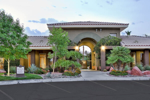 San Croix apartments with elegant clubhouse, rocky landscaping, tall trees, and ample parking.