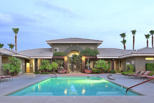 Pool area with lounge chairs, potted plants, gazebos, and tall palm trees.