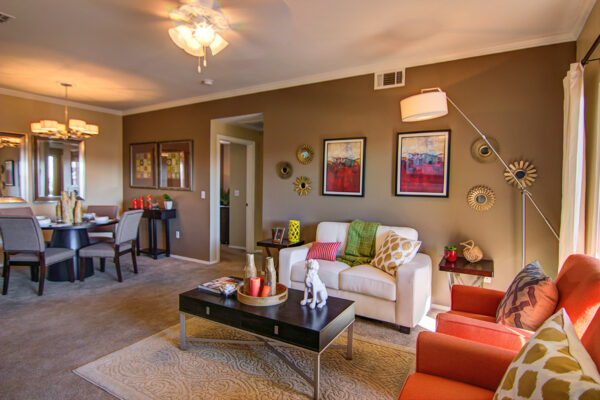 Living room with carpet, plush seating, tables with decor, and artwork.