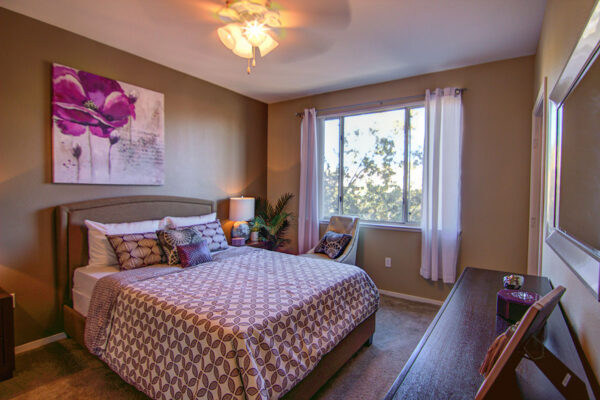 Bedroom with carpet, plush bed, bedside tables with lamps, and large artwork.